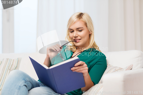 Image of young woman with glasses reading book at home