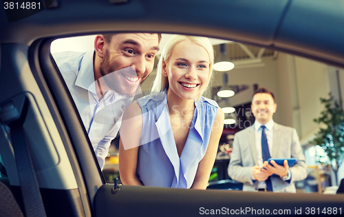 Image of happy couple with car dealer in auto show or salon