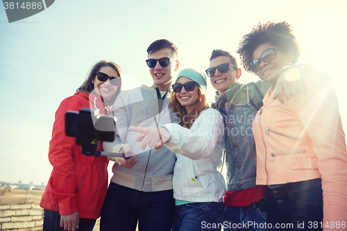 Image of smiling friends taking selfie with smartphone