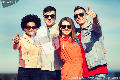 Image of happy teenage friends in shades hugging outdoors