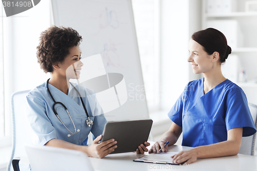 Image of happy doctors with tablet pc meeting at hospital