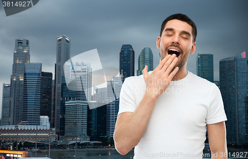 Image of yawning man over evening singapore city background