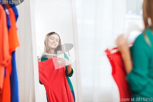 Image of woman with smartphone taking mirror selfie at home