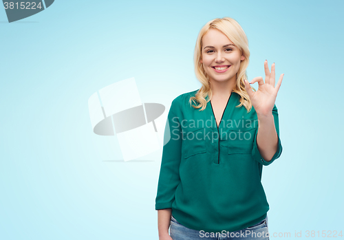 Image of smiling young woman in shirt showing ok hand sign