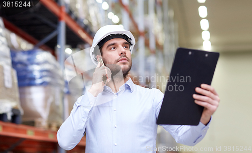 Image of man with clipboard and smartphone at warehouse