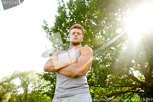 Image of sporty young man with crossed arms at summer park