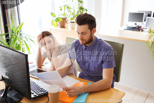 Image of creative team with computer and papers in office