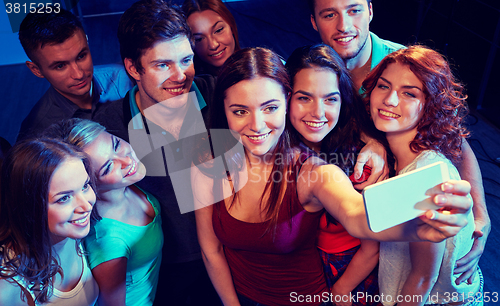 Image of friends with smartphone taking selfie in club