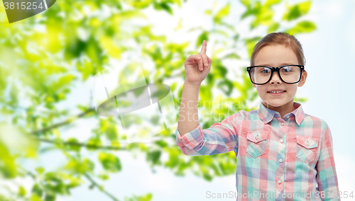 Image of happy little girl in eyeglasses pointing finger up