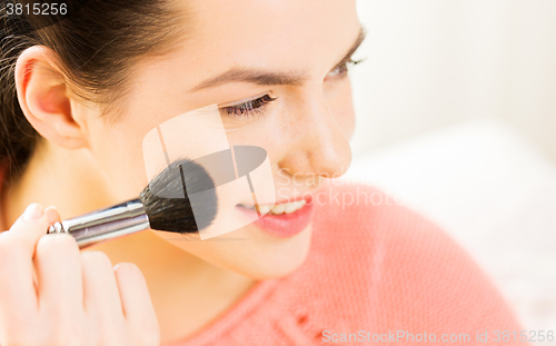 Image of happy woman with makeup brush blushing cheekbone