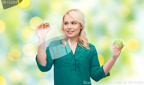 Image of smiling woman choosing between apple and cookie