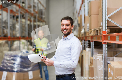 Image of happy businessman with clipboard at warehouse