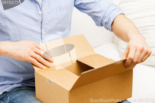 Image of close up of man with cardboard box parcel at home