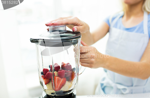 Image of close up of woman with blender making fruit shake