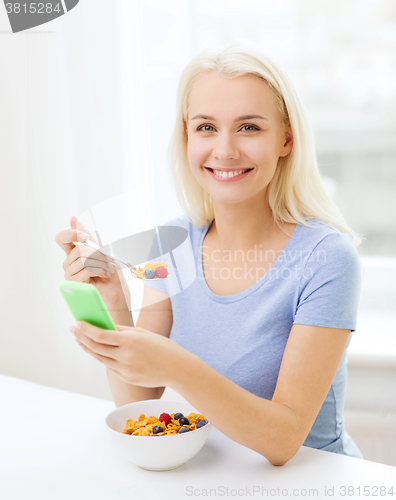 Image of smiling woman with smartphone eating  breakfast 