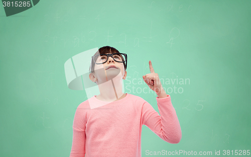 Image of happy little girl in eyeglasses pointing finger up