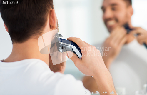 Image of close up of man shaving beard with trimmer