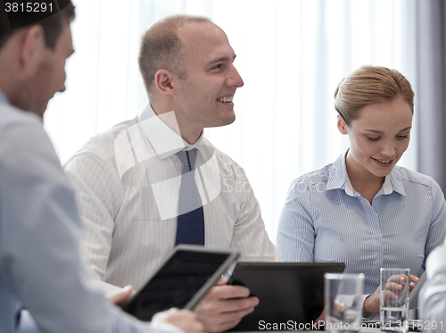 Image of smiling businesspeople with tablet pc in office
