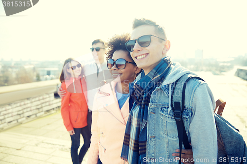 Image of happy teenage friends in shades hugging on street