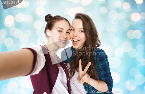 Image of happy friends taking selfie and showing peace