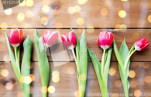 Image of close up of red tulip flowers on wooden table