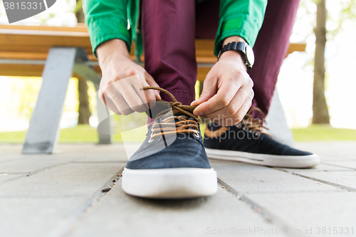 Image of close up of male hands tying shoe laces on street