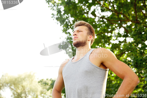 Image of sporty young man with crossed arms at summer park