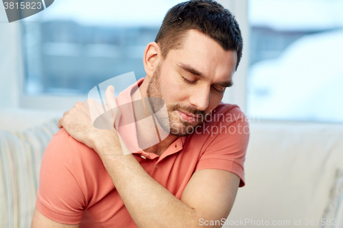 Image of unhappy man suffering from neck pain at home