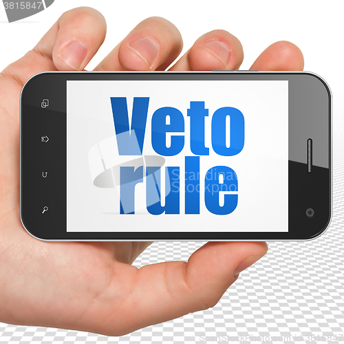 Image of Political concept: Hand Holding Smartphone with Veto Rule on display