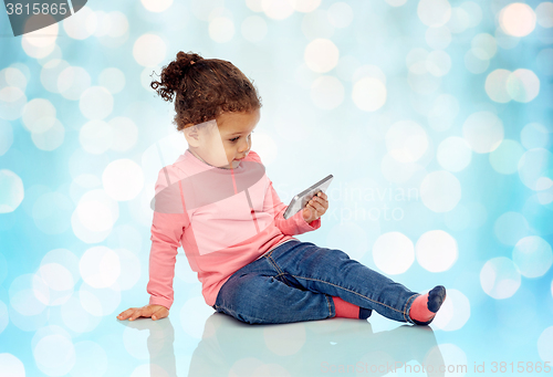 Image of smiling little baby girl playing with smartphone
