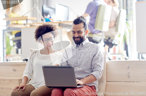 Image of happy creative team with laptop in office