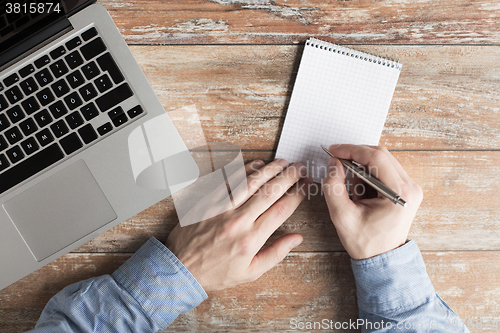 Image of close up of male hands with laptop and notebook