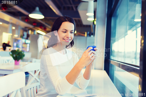 Image of smiling woman with smartphone at cafe