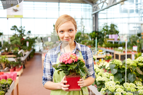 Image of happy woman holding flowers in greenhouse or shop