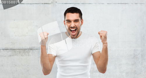 Image of young man celebrating victory over gray