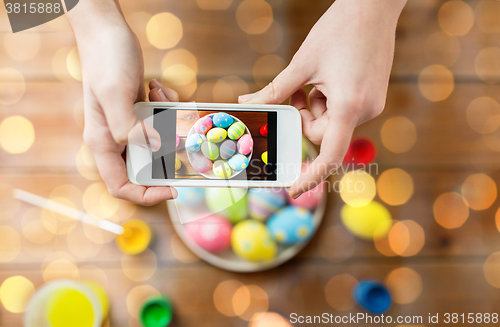 Image of close up of hands with easter eggs and smartphone