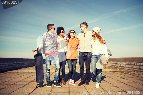 Image of happy teenage friends with longboards on street