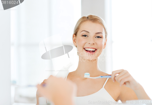 Image of woman with toothbrush cleaning teeth at bathroom