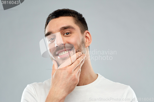 Image of happy young man touching his face or beard