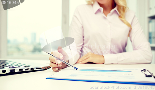 Image of smiling businesswoman reading papers in office