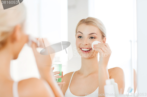 Image of young woman with lotion washing face at bathroom