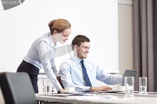 Image of businessman and secretary with laptop in office