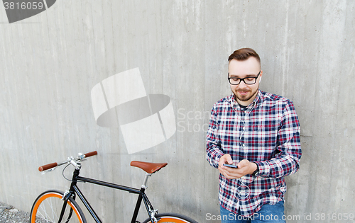 Image of hipster man in earphones with smartphone and bike