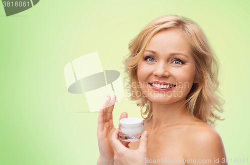 Image of happy woman applying cream to her face