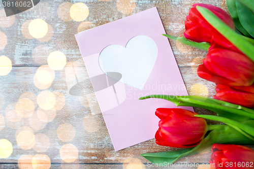 Image of close up of tulips and greeting card with heart