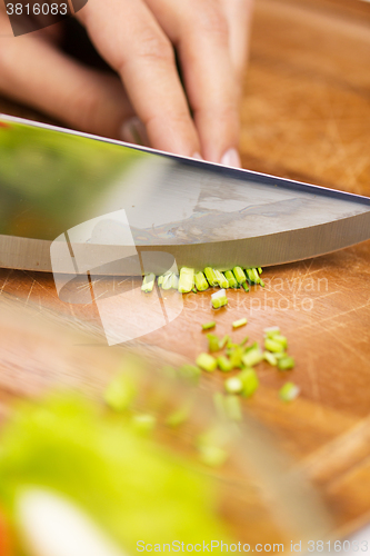 Image of close up of woman chopping green onion with knife