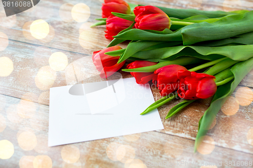 Image of close up of red tulips and blank paper or letter