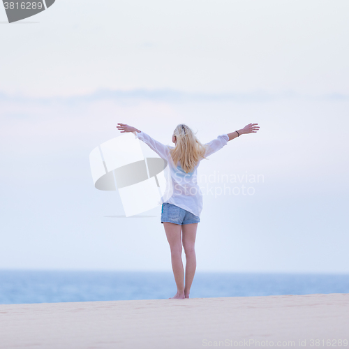 Image of Free woman enjoying freedom on beach in morning.