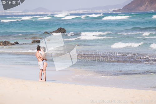 Image of Young couple kissing on sandy beach.