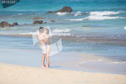 Image of Young couple kissing on sandy beach.